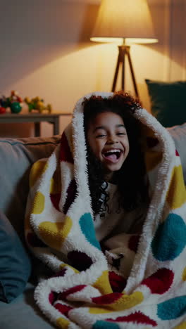 joyful child snuggled in a cozy blanket at home