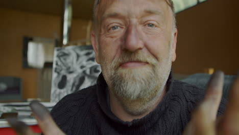 painter, artist smiles at the camera and shows his dirty hands from charcoal