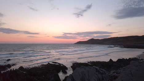 waves crashing against a sandy beach at dusk during summer in slow motion