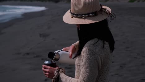 young woman drinking mate on the beach, pichilemu punta de lobos chile, serving mate, slow motion