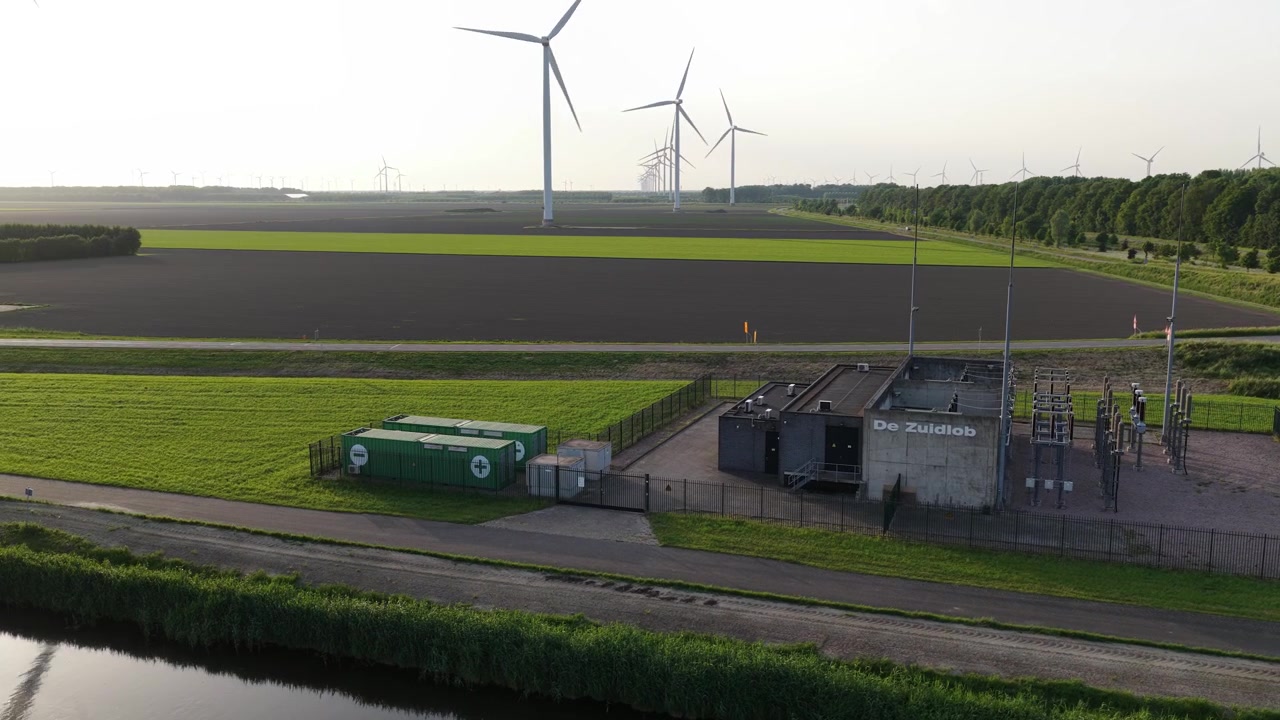 Aerial view of Dutch renewable energy infrastructure with wind turbines, power substation and battery energy storage system supporting the electricity grid.