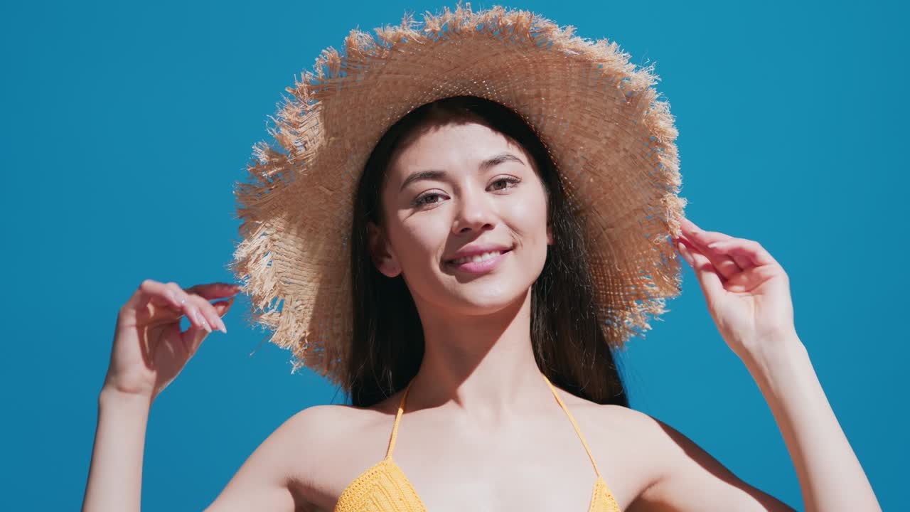 Asian girl in a straw hat turns around and smiles for the camera