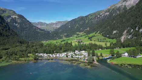 plenty-white-camper-vans-of-different-sizes-parked-up-in-a-nature-resort-by-the-water-shore-in-the-middle-of-nowhere-in-the-mountains-with-incredible-views-of-the-mountains-cinematic-holiday-lake-sky