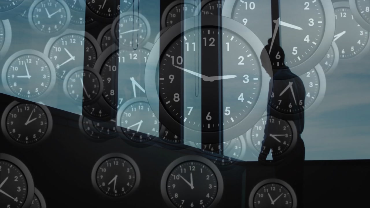 Clocks showing different times over silhouette of person by large windows