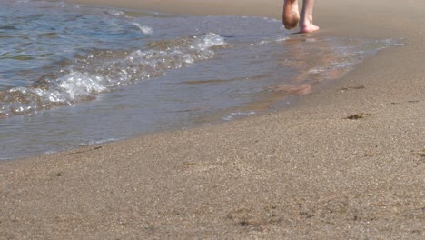 man walking barefoot on beach, along waves, freedom concept, low angle