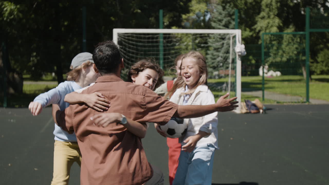 Joyful reunion of an adult and children on a soccer field