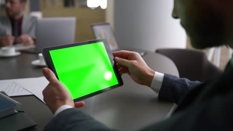 businessman using tablet device green screen looking corporate news in workplace