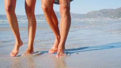 Nahaufnahme-Von-Paarbeinen,-Die-Im-Strandurlaub-Entlang-Der-Küste-Spazieren