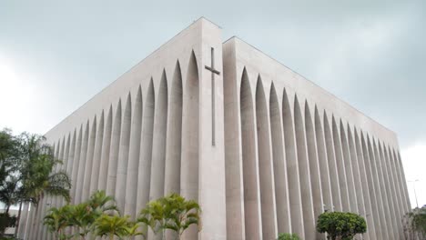 vista exterior de la iglesia dom bosco en brasilia - pan shot - día nublado con árboles afuera