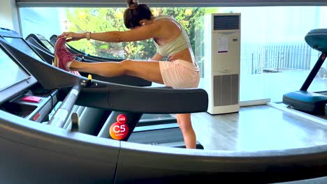 Mujer-Haciendo-Ejercicios-De-Estiramiento-En-Cinta-Rodante,-En-El-Gimnasio.