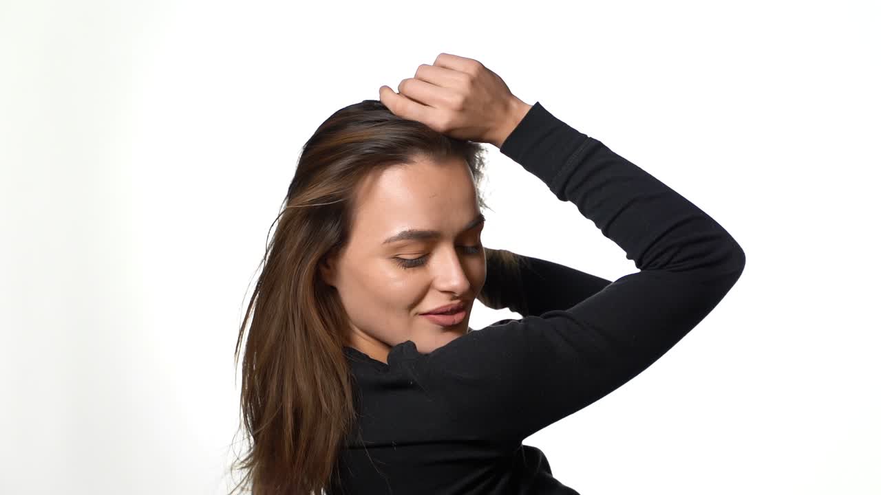 Woman with hairstyle trembling from laugh. Smiling positively and being in great mood while standing over white background