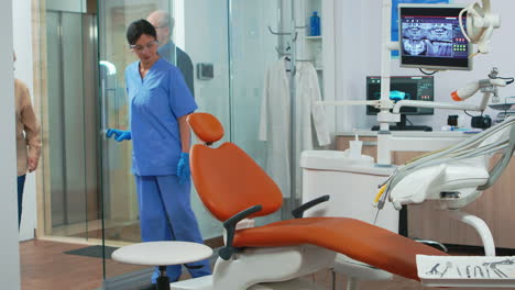 nurse inviting senior woman in consultation dental room