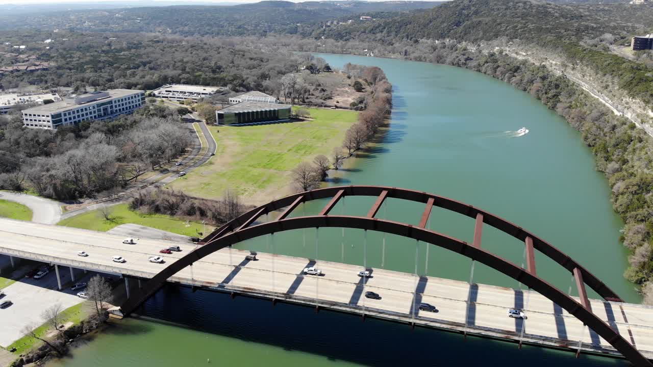 Aerial Austin Pennybacker Bridge - moving towards and then  over the bridge while a boat begins to  move upstream, bridge nearly out of view at the end of clip.