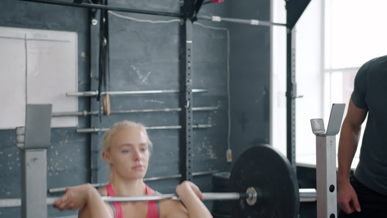 Woman Weightlifting with Coach in Gym