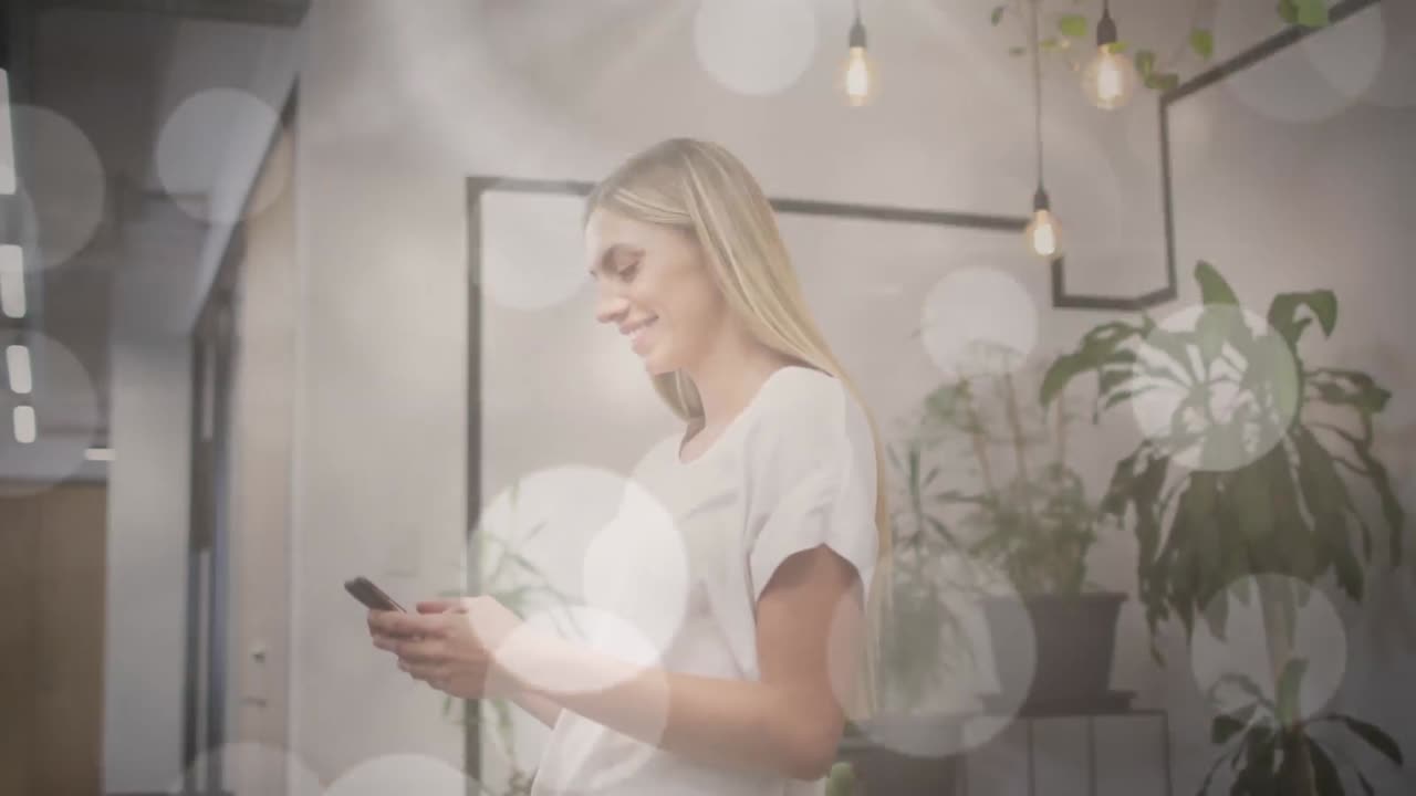 사무실에서 스마트폰을 사용하는 행복한 백인 여성 위에 보케 빛 반점의 애니메이션