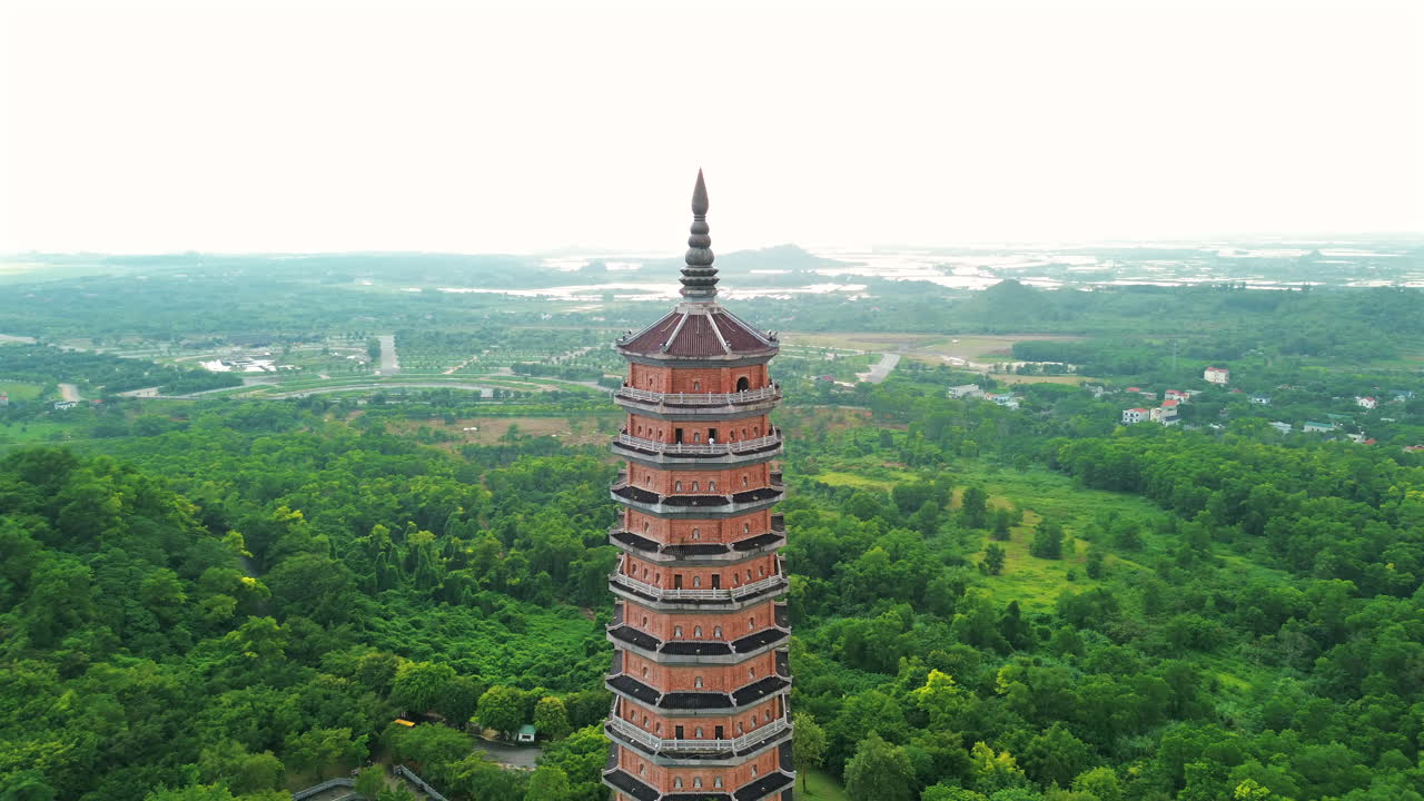 Et luftperspektiv omkring det 100 meter høje Bao Thap Tårn, Asiens højeste buddhistiske stupa, der fremviser dens intrikate 13-etagers arkitektur midt i de frodige skove i Ninh Binh, Vietnam.