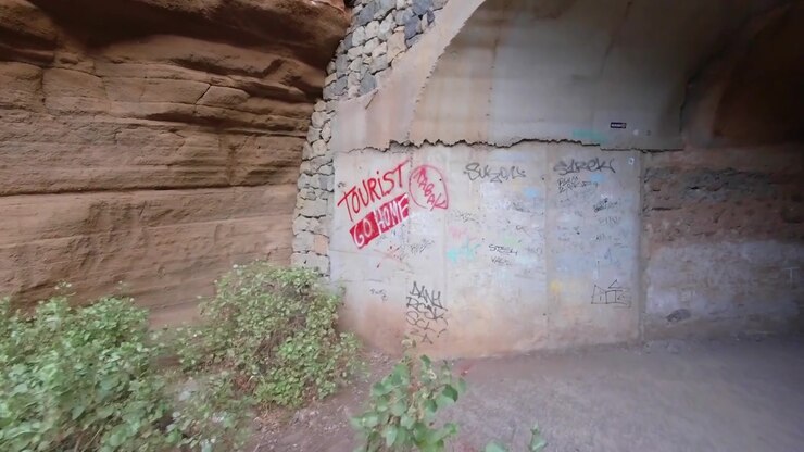 Ingresso del tunnel che conduce al Barranco de las Vaces a Gran Canaria con il graffito: Turisti, tornate a casa.