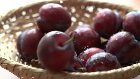 a bounty of fresh, juicy plums: a close-up view of ripe stone fruits glistening with dew in a woven basket, perfectly showcasing their luscious red skin
