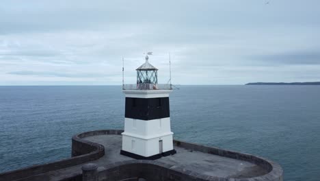 Holyhead-breakwater-lighthouse-longest-concrete-coastal-sea-protection-landmark-aerial-view-low-pull-away-rotating-right