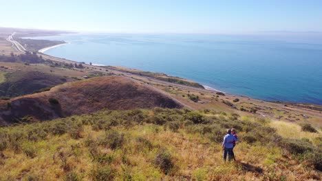 Antenne-Rentnerehepaar,-Das-Am-Berggipfel-Steht,-Mit-Blick-Auf-Das-Meer-Oder-Die-Küste-Auf-Einer-Ranch-In-Der-Nähe-Von-Santa-Barbara,-Kalifornien?