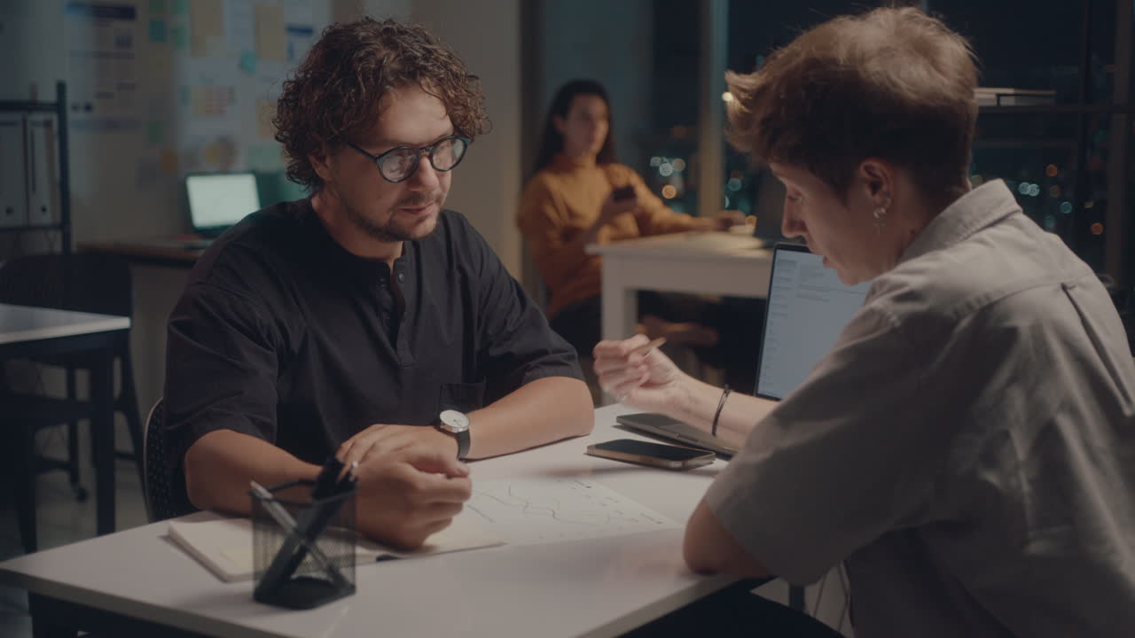 Colleagues Discussing Business Papers in Office at Night