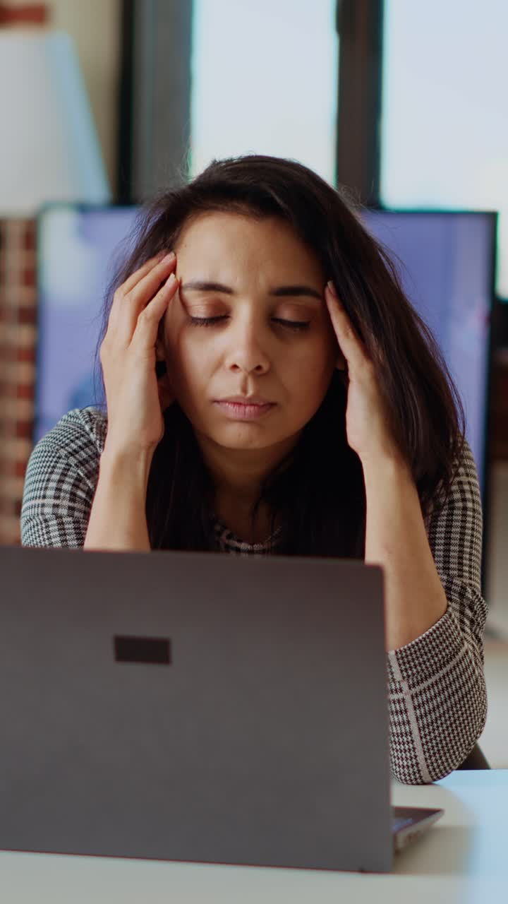 Video verticale: un* freelancer esaust* soffre di malessere e stress mentre lavora al laptop