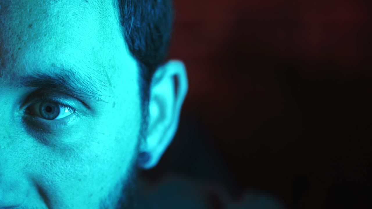 hombre atento que trabaja en el primer plano del estudio de iluminación de colores mezclados