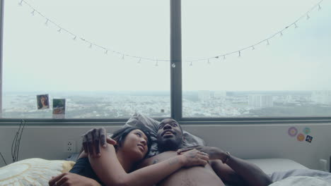 young couple hugging and talking in bed beside the window