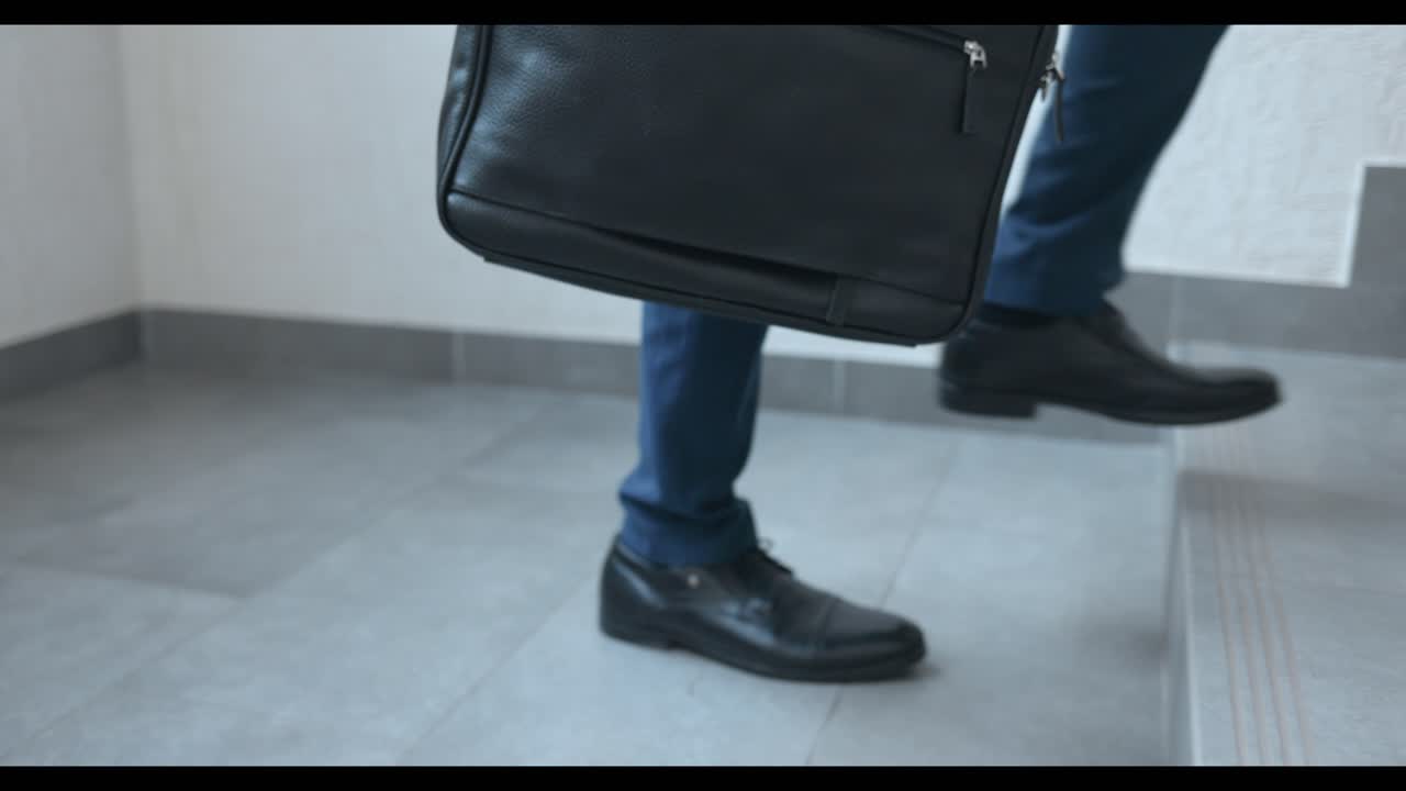 Business professional ascending modern staircase while carrying a black briefcase for work