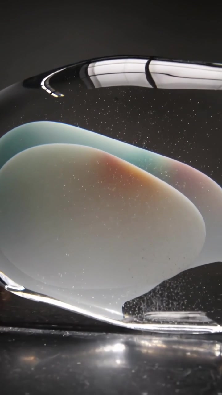 Vertical video: Panning camera revealing glass sculpture in studio, exposing teal core bubbles