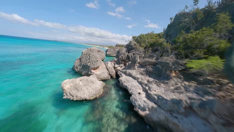 FPV-drone-flight-along-rocky-coastline-and-tropical-sandy-beach