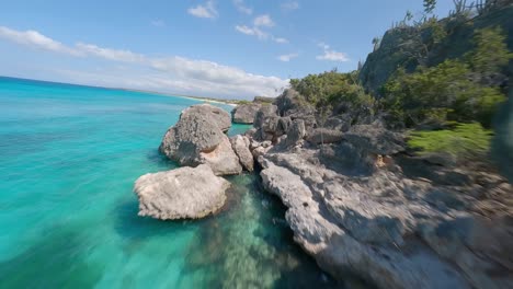 fpv drone flight along rocky coastline and tropical sandy beach