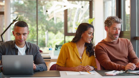 multi-cultural business team meeting around laptop in modern office
