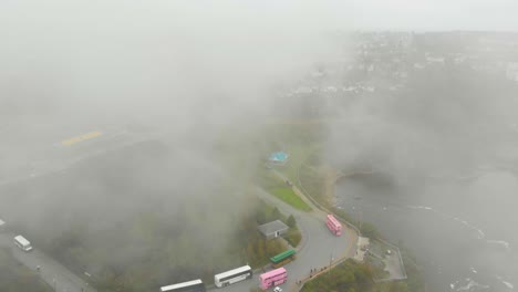 aerial shot traveling through the clouds towards a neighborhood on a cloudy day