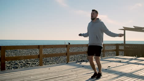 man jumping rope on a beach pier