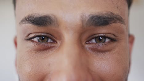 Portrait-close-up-of-green-eyes-of-happy-biracial-man-smiling,-copy-space,-in-slow-motion
