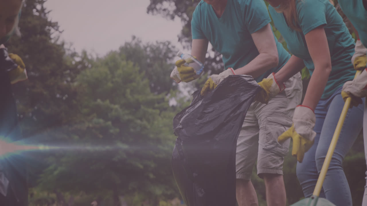 Video of lights over happy caucasian family picking up rubbish in countryside
