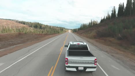 aerial drone shot following a silver truck on the road