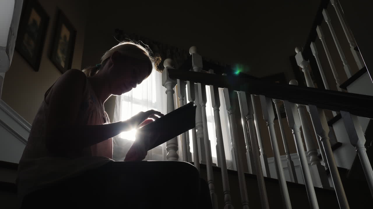 mujer usa tableta en una escalera