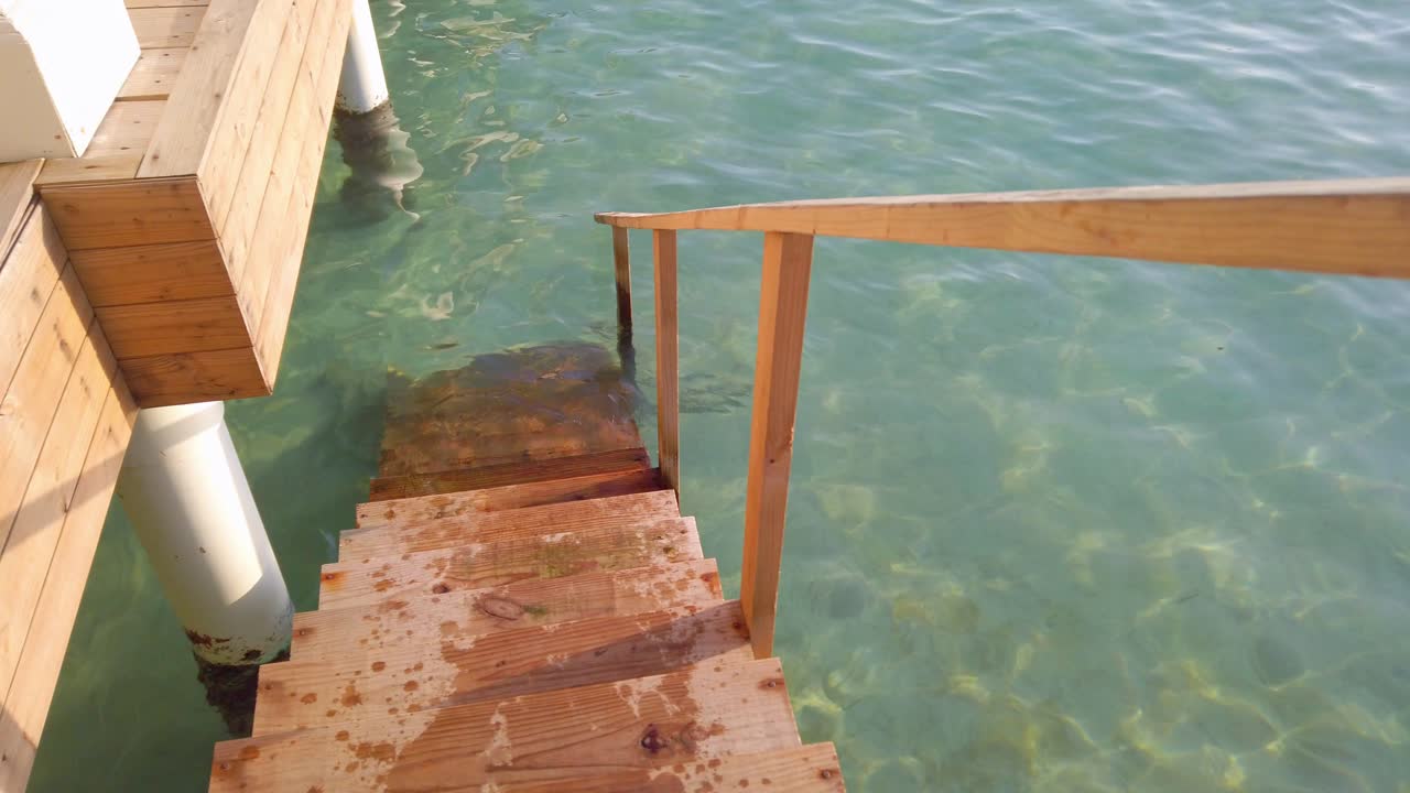 деревянная лестница океанической виллы, ведущая вниз в воду
