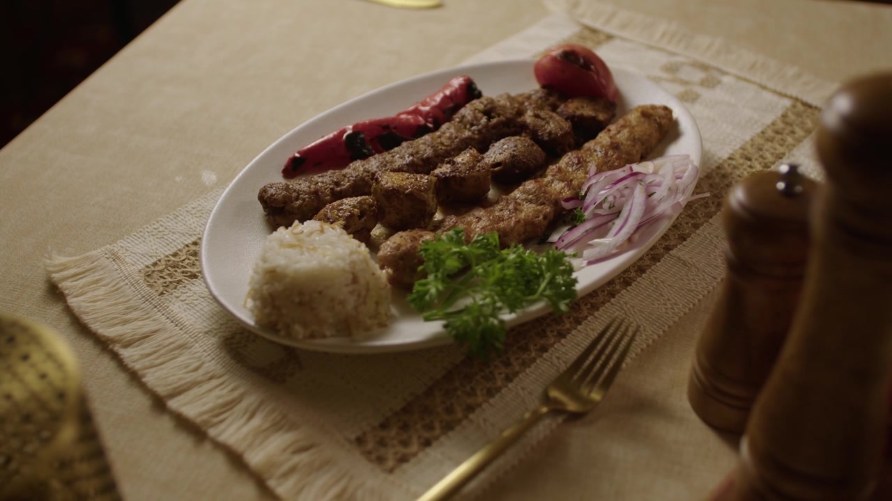 Grilled kebab platter with rice, onions, and herbs served on a decorated table