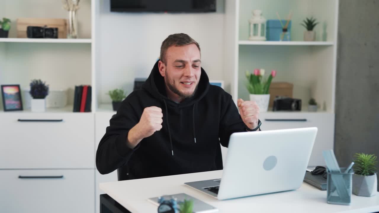 The man is sitting behind the laptop, rooting for someone, rejoicing in the victory, and can't believe his eyes