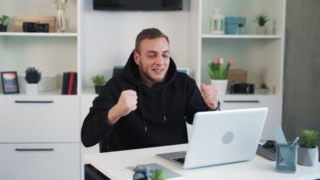 The man is sitting behind the laptop, rooting for someone, rejoicing in the victory, and can&#039;t believe his eyes