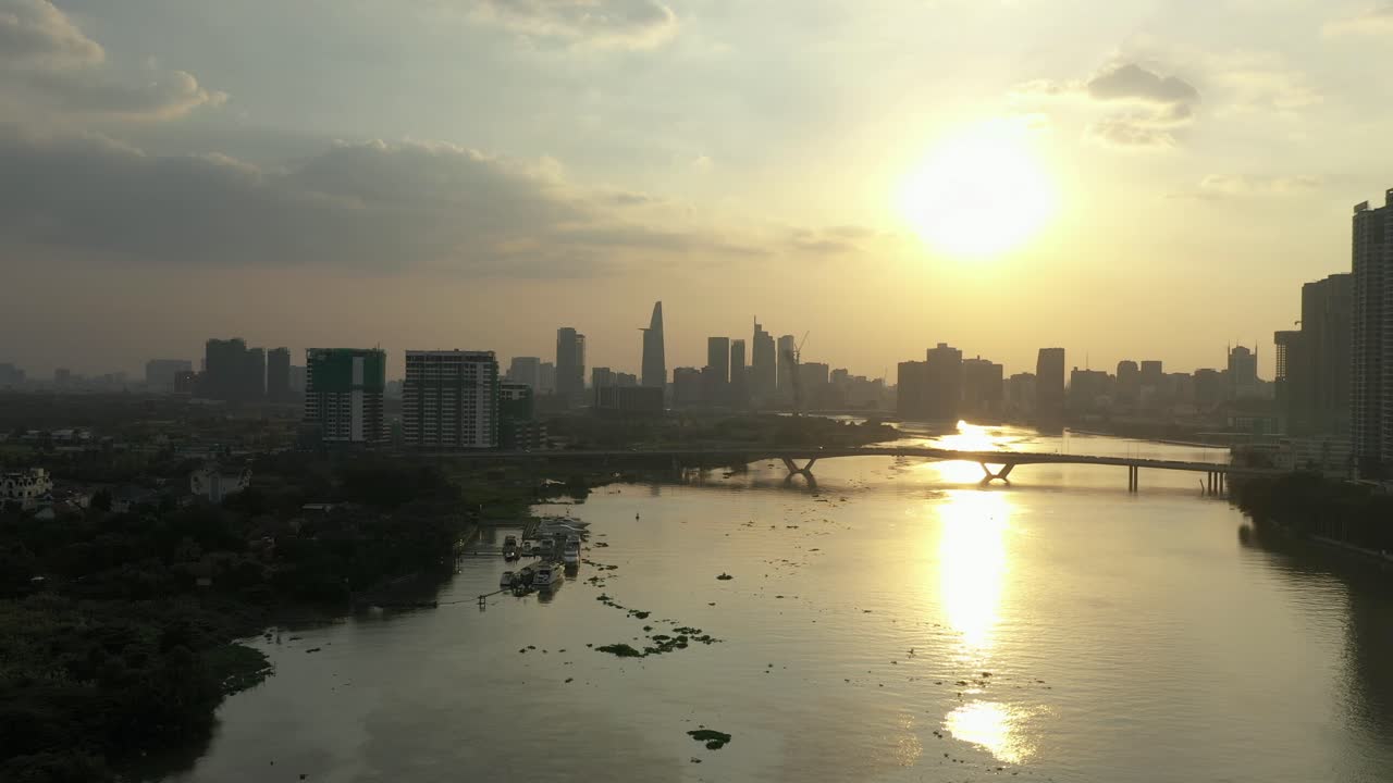 베트남 사이곤 강을 가로질러 드론에서 다리와 해가 지는 현대 도시 스카이 라인을 볼 수 있습니다.