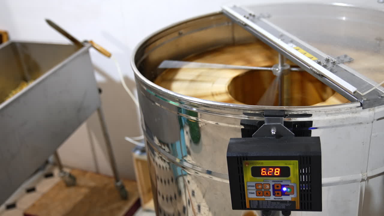 Metal electronic centrifuge device rotating the wooden frames with honeycombs. Extraction of organic honey at apiary.