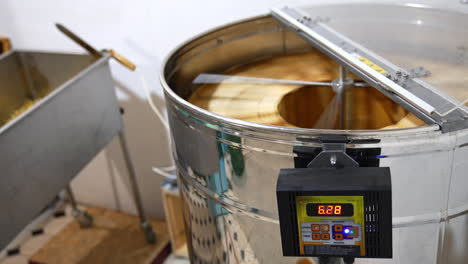 metal electronic centrifuge device rotating the wooden frames with honeycombs. extraction of organic honey at apiary.