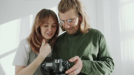 cheerful woman and photographer checking photos and talking in studio