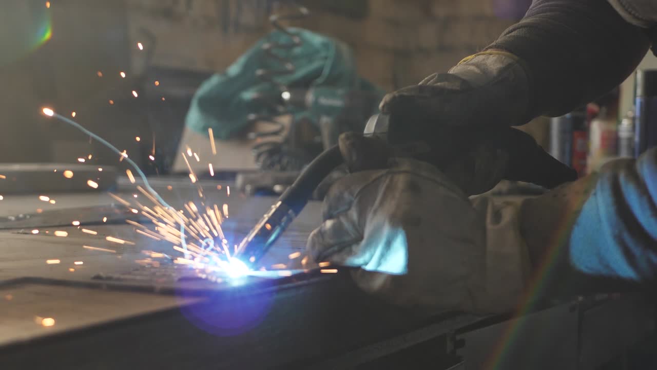 Welder on the table welds a set of metal parts