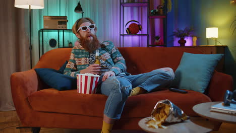 man watching tv on the couch with popcorn and beer