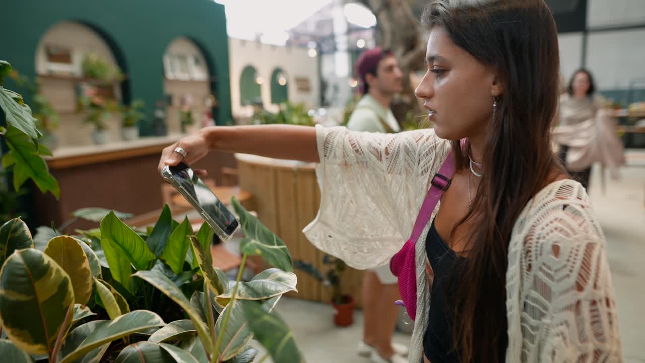 Woman taking a picture of indoor plants at a retail store